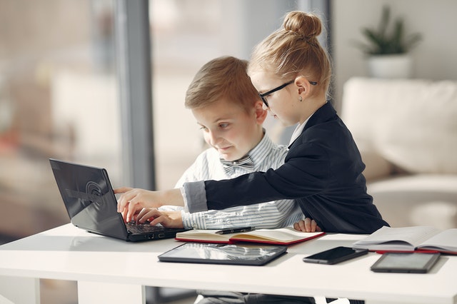 Barn hjälper annan barn att använda dator